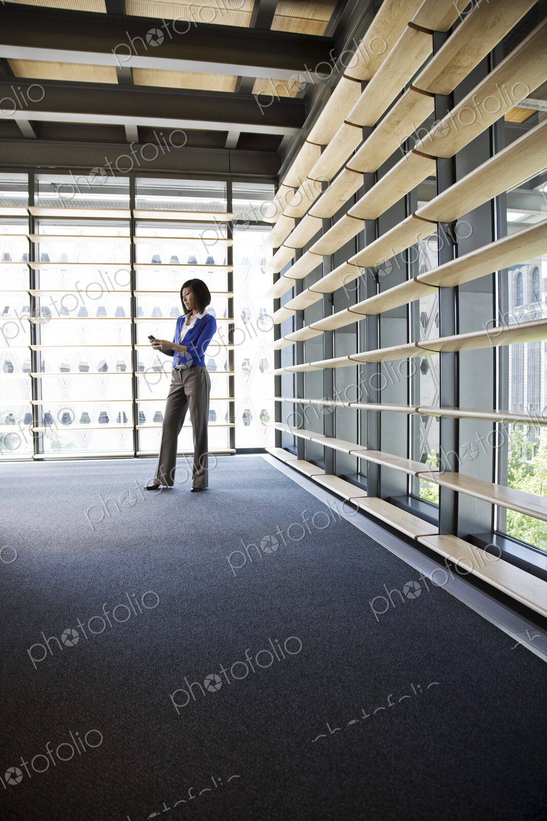 Asian businesswoman texting from the lobby of a large office building.
