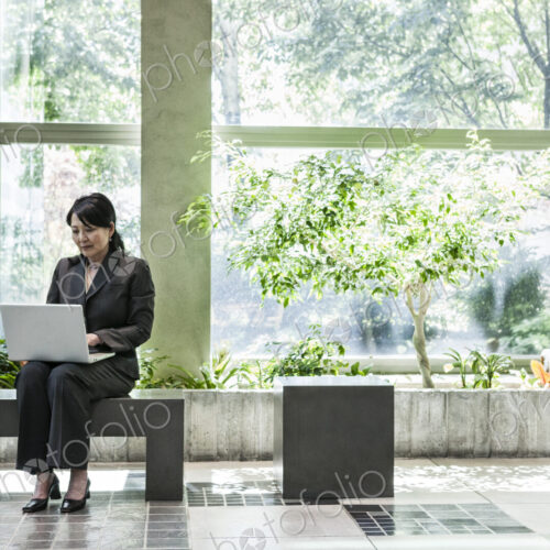 Asian businesswoman working in a large open lobby area.