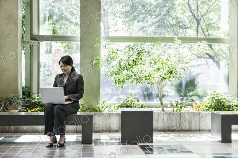 Asian businesswoman working in a large open lobby area.