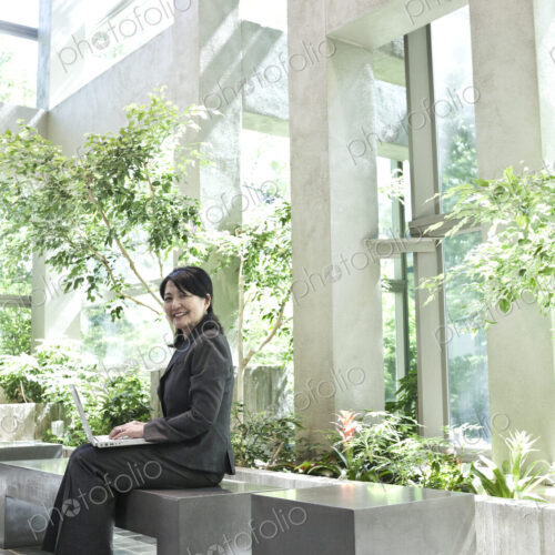 Asian businesswoman working in a large open lobby area.