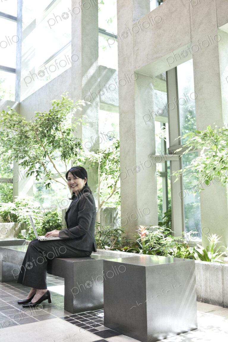 Asian businesswoman working in a large open lobby area.