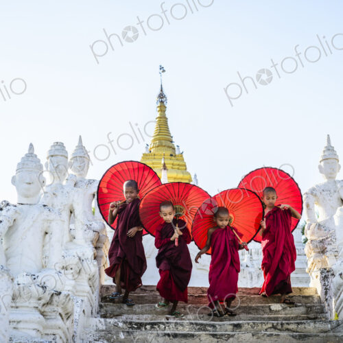 Asian children with parasols balancing on Buddhist shrine Asian children with parasols balancing on Buddhist shrine