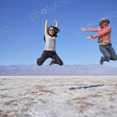 Asian couple jumping near mountain range Asian couple jumping near mountain range