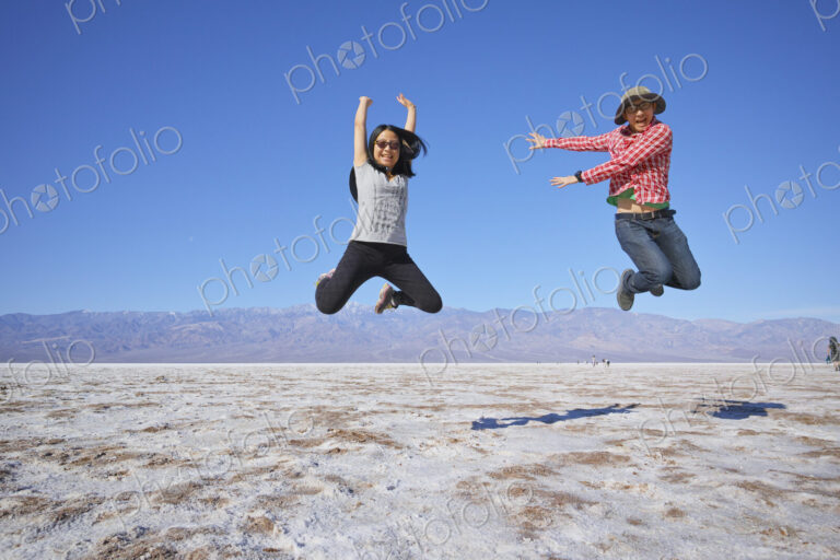 Asian couple jumping near mountain range