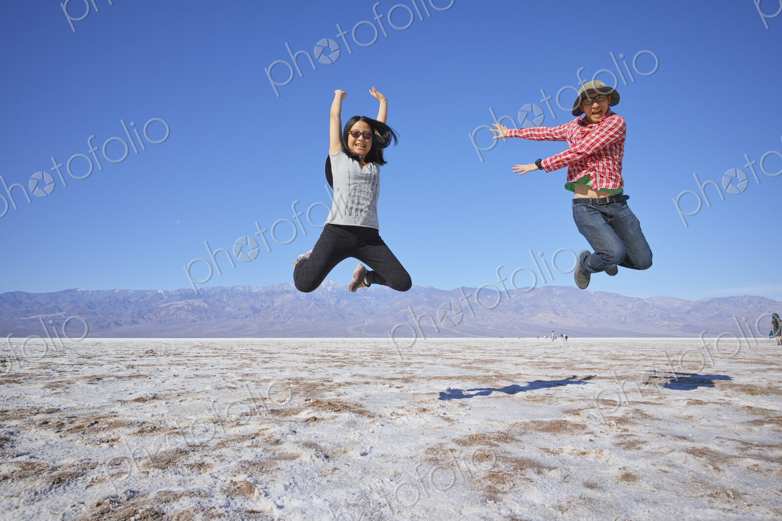 Asian couple jumping near mountain range