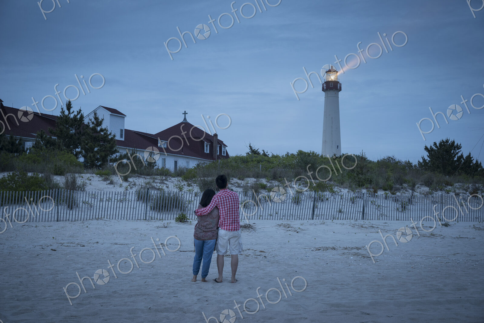 Asian couple watching lighthouse at beach