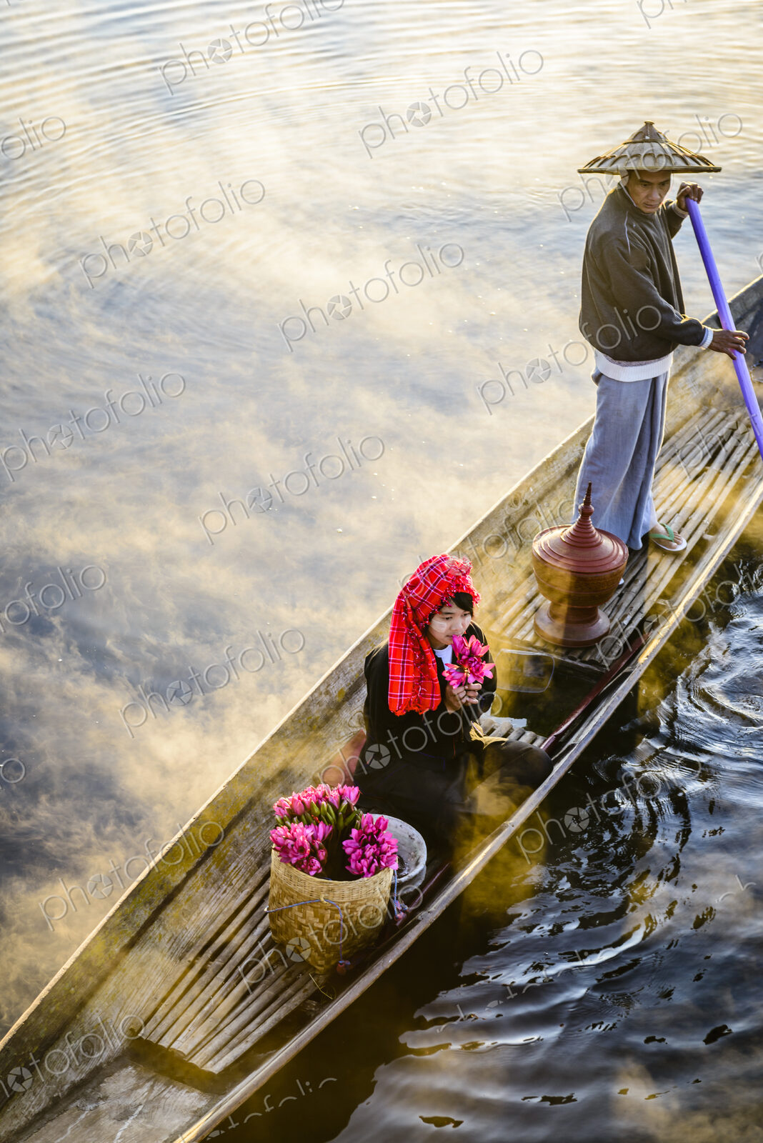 Asian farmer and daughter rowing in canoe on river