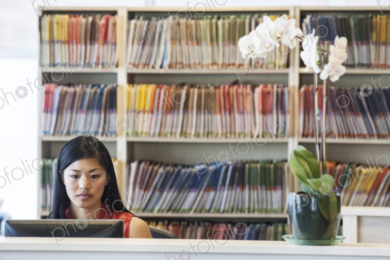 Asian female working in a medical office with file folders in the background