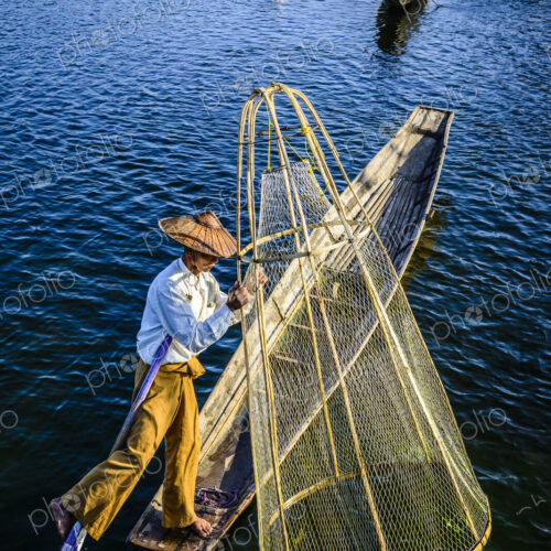 Asian fisherman fishing in canoe on river Asian fisherman fishing in canoe on river