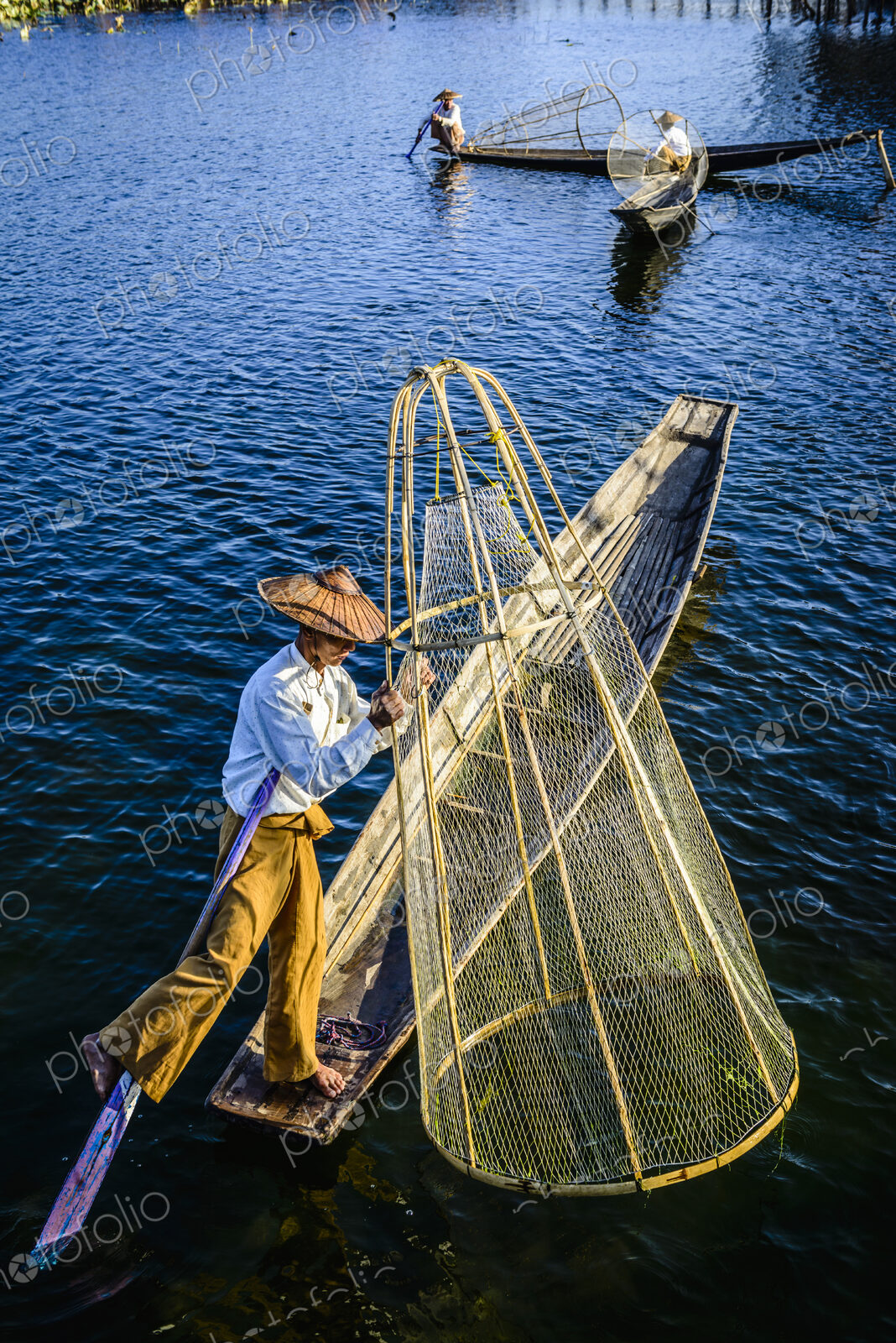 Asian fisherman fishing in canoe on river