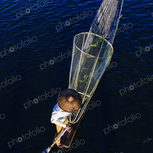 Asian fisherman fishing in canoe on river Asian fisherman fishing in canoe on river