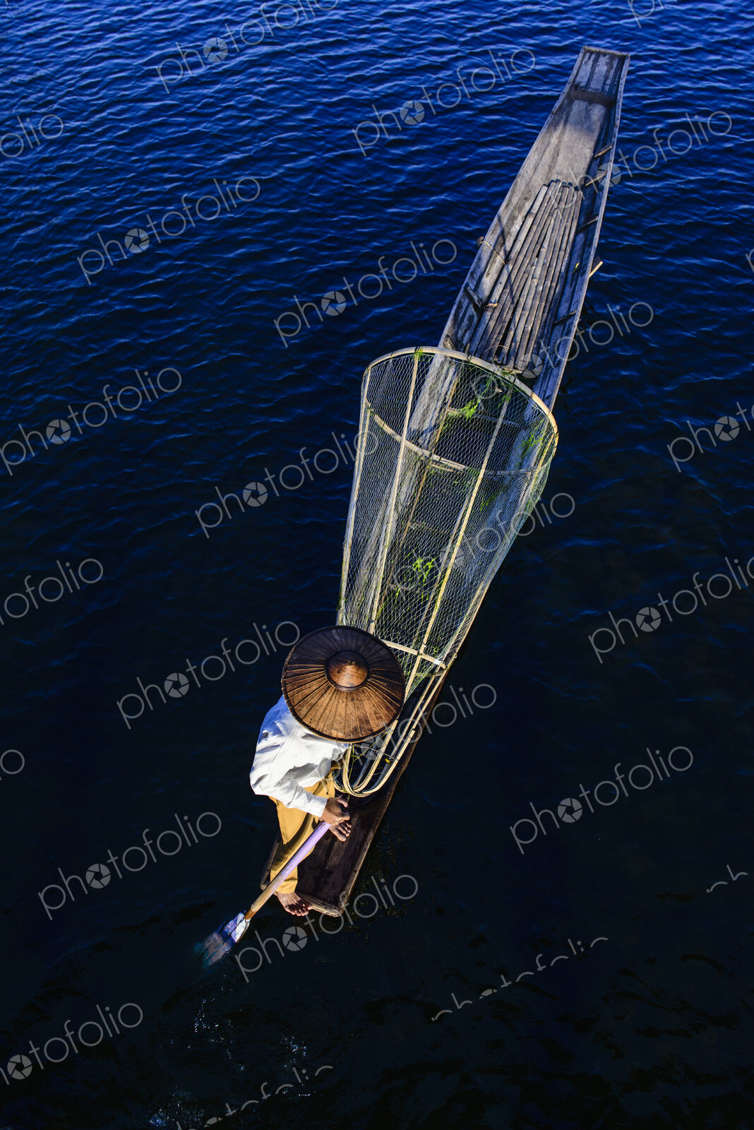 Asian fisherman fishing in canoe on river