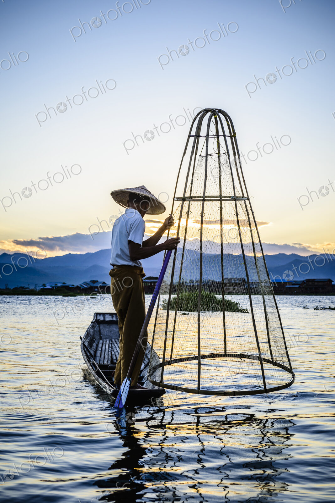 Asian fisherman using fishing net in canoe on river