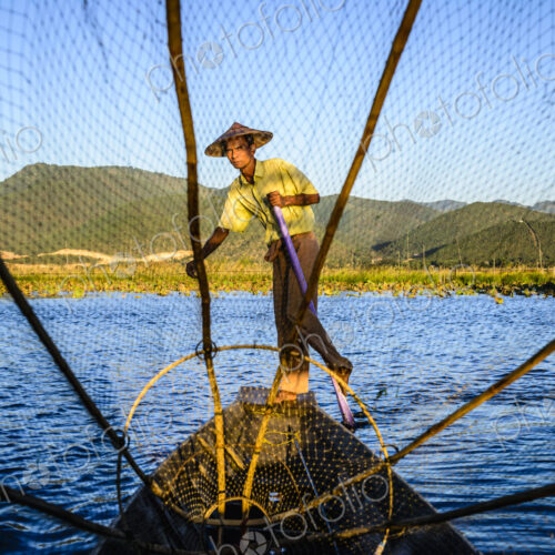 Asian fisherman using fishing net in canoes on river Asian fisherman using fishing net in canoes on river