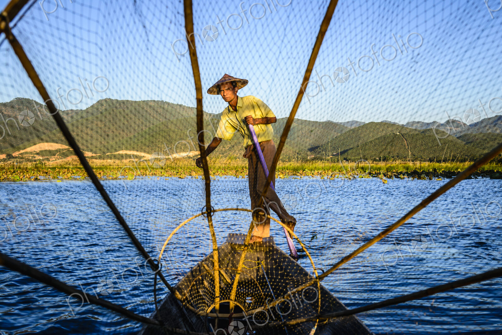 Asian fisherman using fishing net in canoes on river