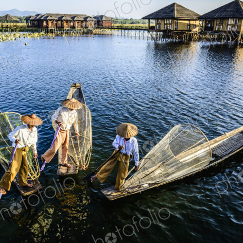 Asian fishermen fishing in canoes on river Asian fishermen fishing in canoes on river