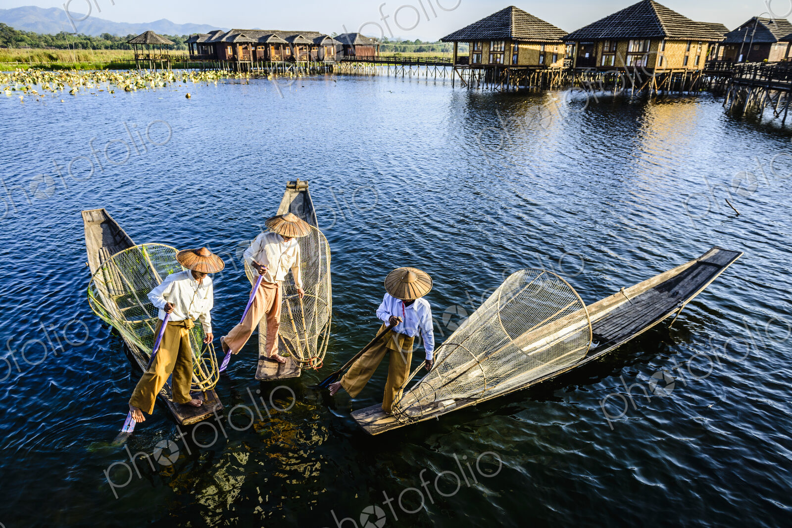 Asian fishermen fishing in canoes on river