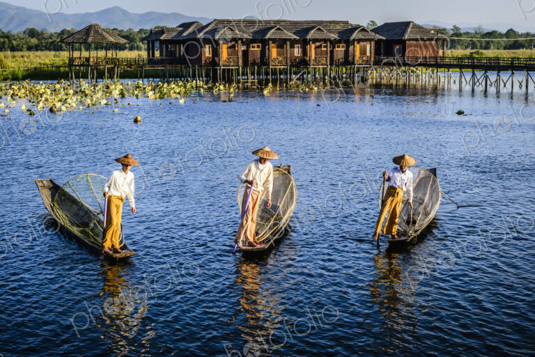 Asian fishermen fishing in canoes on river