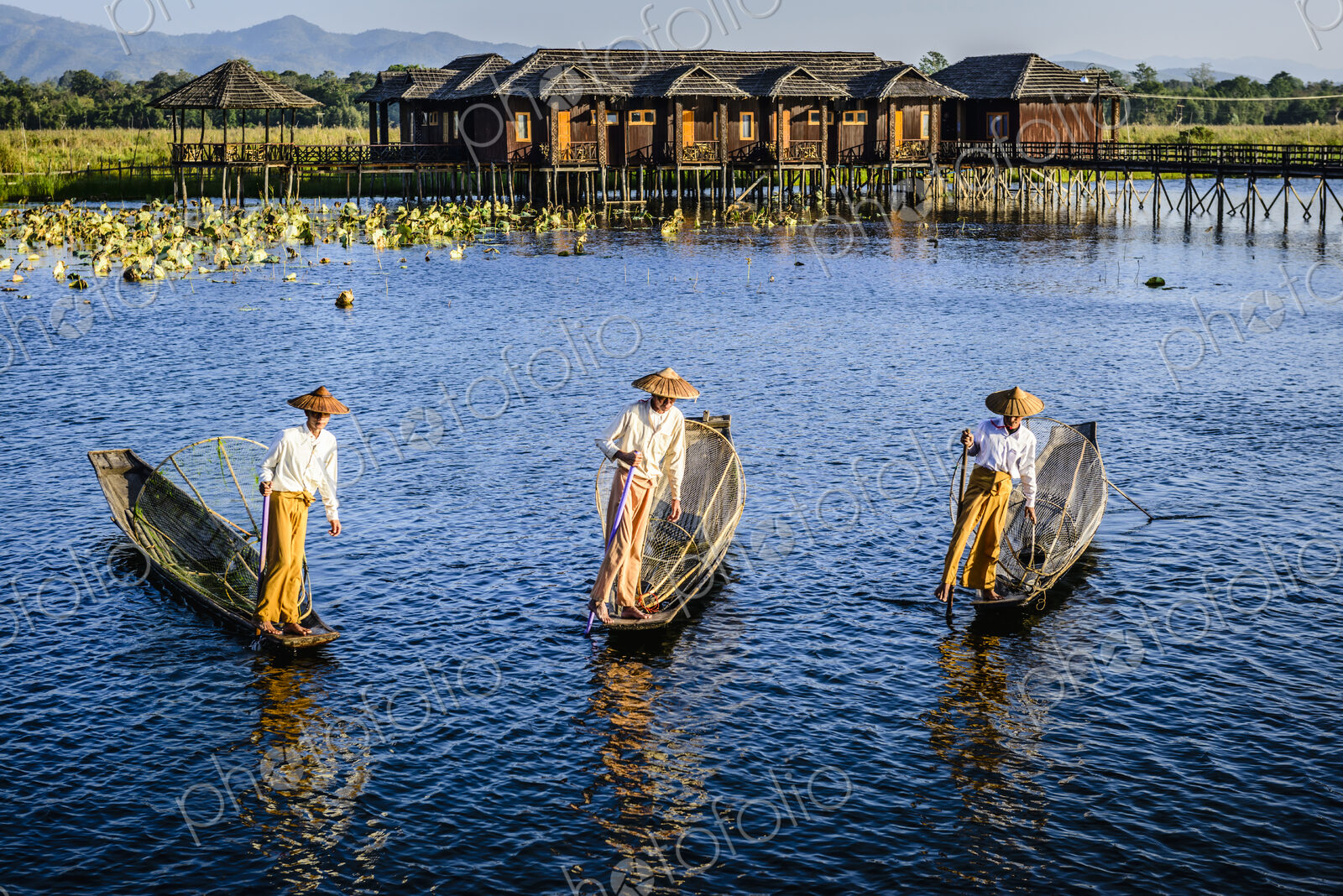 Asian fishermen fishing in canoes on river