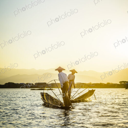 Asian fishermen fishing in canoes on river Asian fishermen fishing in canoes on river