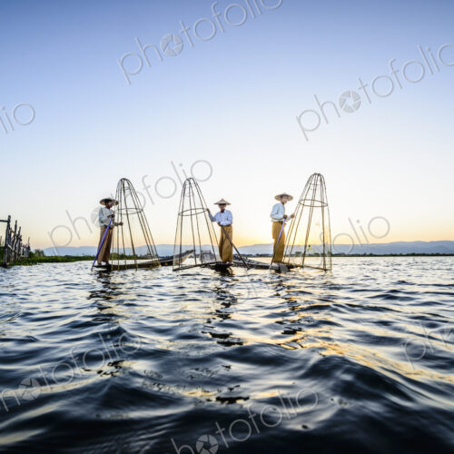 Asian fishermen fishing in canoes on river Asian fishermen fishing in canoes on river
