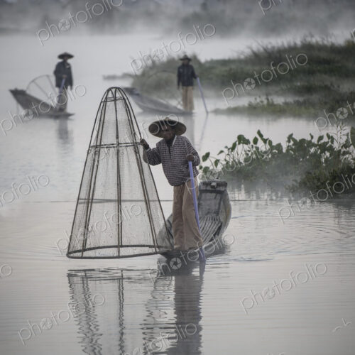 Asian fishermen fishing in canoes on river Asian fishermen fishing in canoes on river