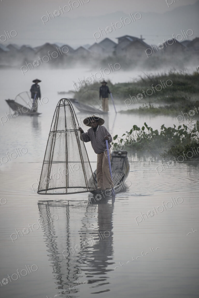 Asian fishermen fishing in canoes on river
