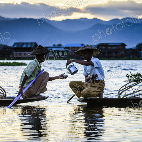 Asian fishermen sharing tea in canoes on river Asian fishermen sharing tea in canoes on river