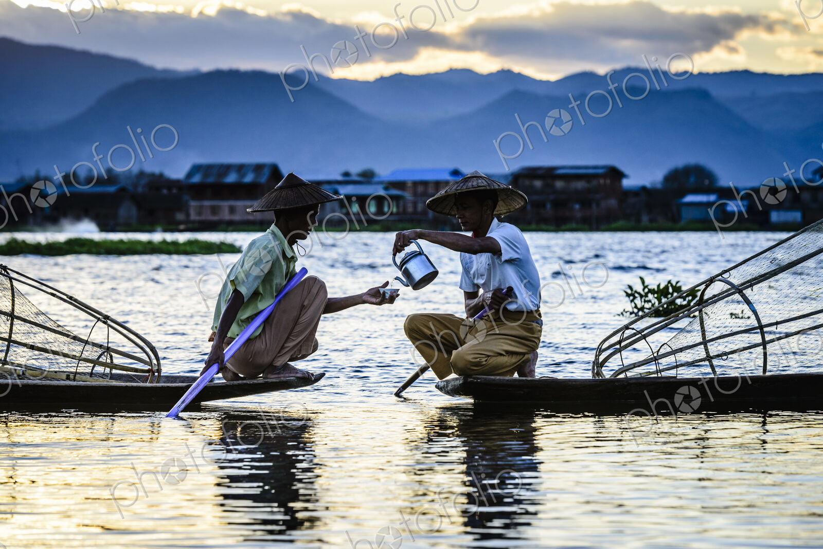 Asian fishermen sharing tea in canoes on river