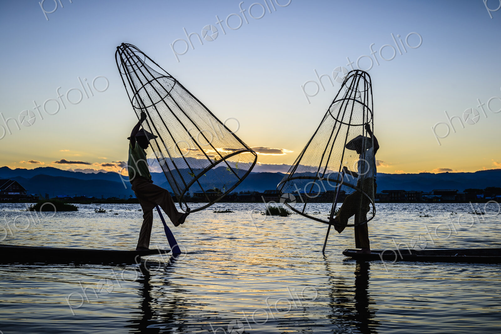 Asian fishermen using fishing nets in canoe on river