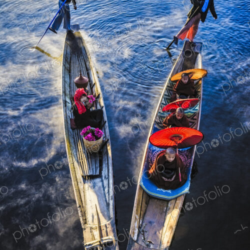 Asian gondoliers rowing canoes on river Asian gondoliers rowing canoes on river