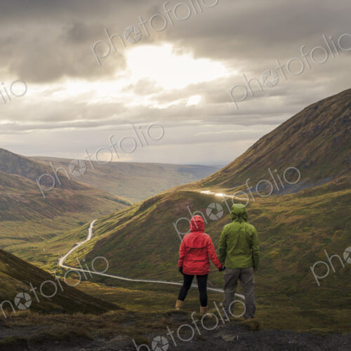 Asian hikers holding hands admiring scenic view of valley Asian hikers holding hands admiring scenic view of valley
