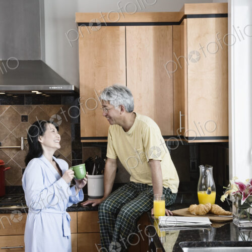 Asian man and woman in their new kitchen for breakfast.