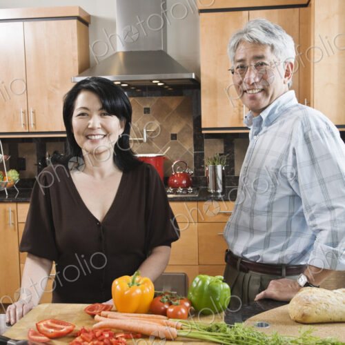 Asian man and woman preparing fresh vegetables in their kitchen. Asian man and woman preparing fresh vegetables in their kitchen.