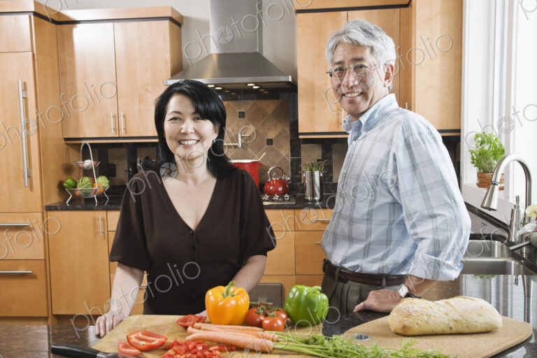 Asian man and woman preparing fresh vegetables in their kitchen.