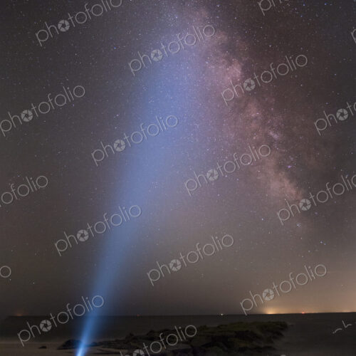Asian man shining flashlight on starry sky