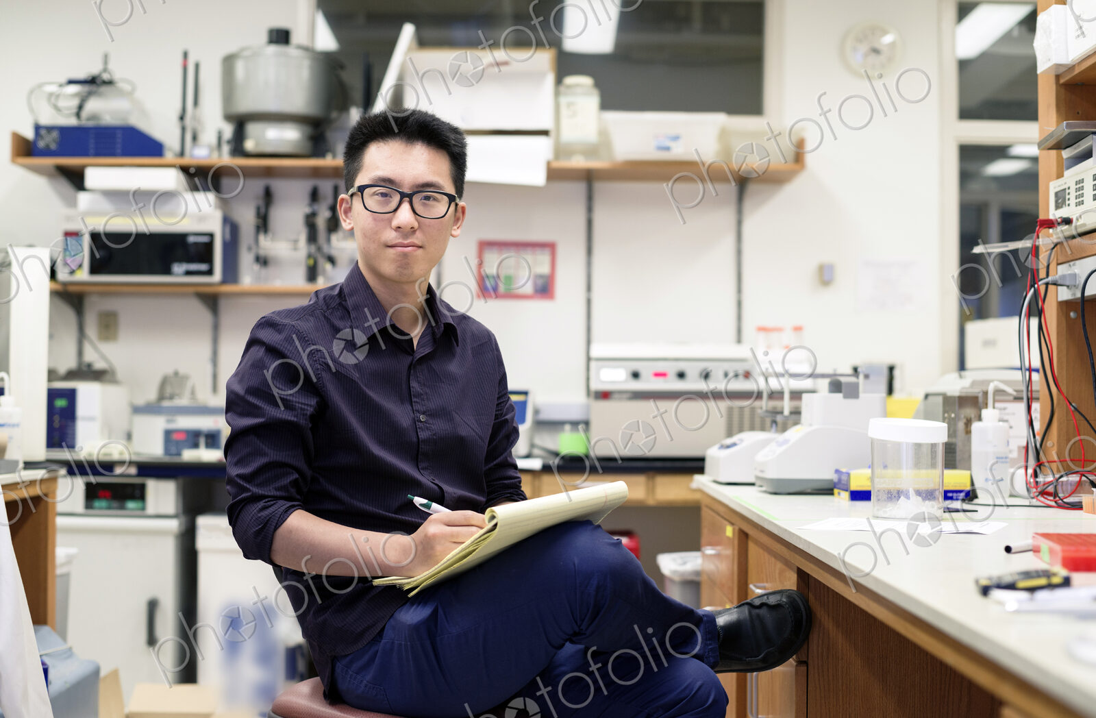Asian man writing on notepad in electronics workshop