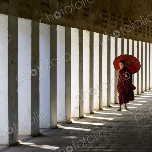 Asian monk-in-training carrying parasol in hallway Asian monk-in-training carrying parasol in hallway