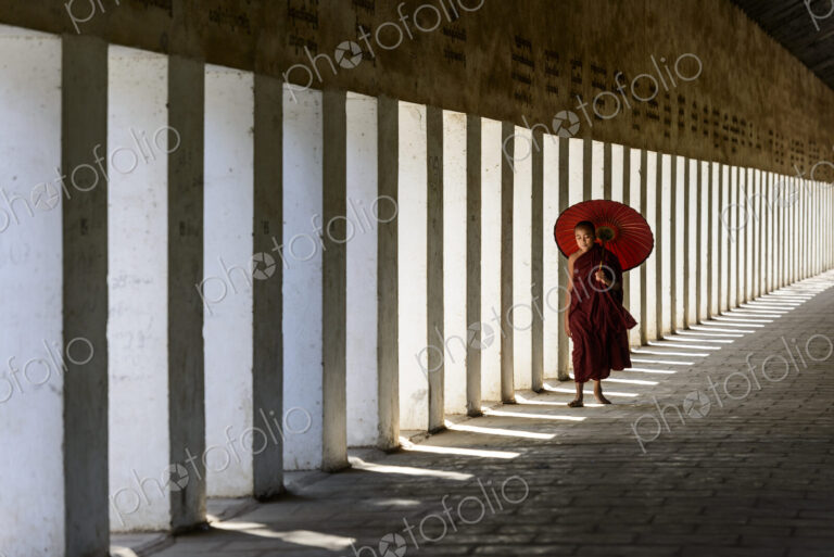 Asian monk-in-training carrying parasol in hallway