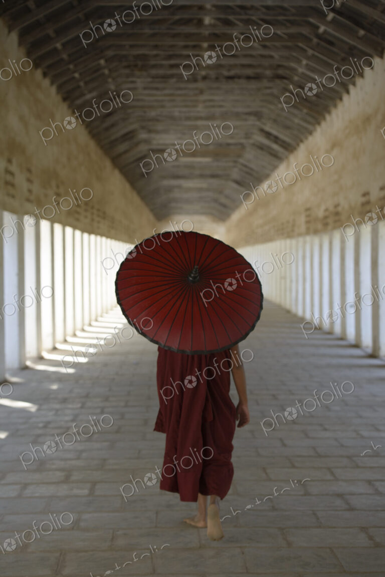 Asian monk-in-training carrying parasol in hallway