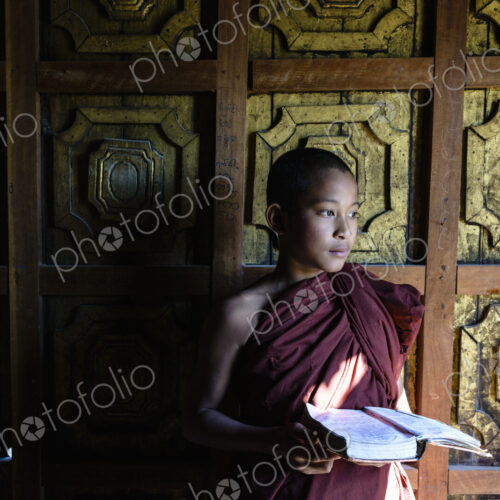 Asian monk-in-training holding book in temple Asian monk-in-training holding book in temple
