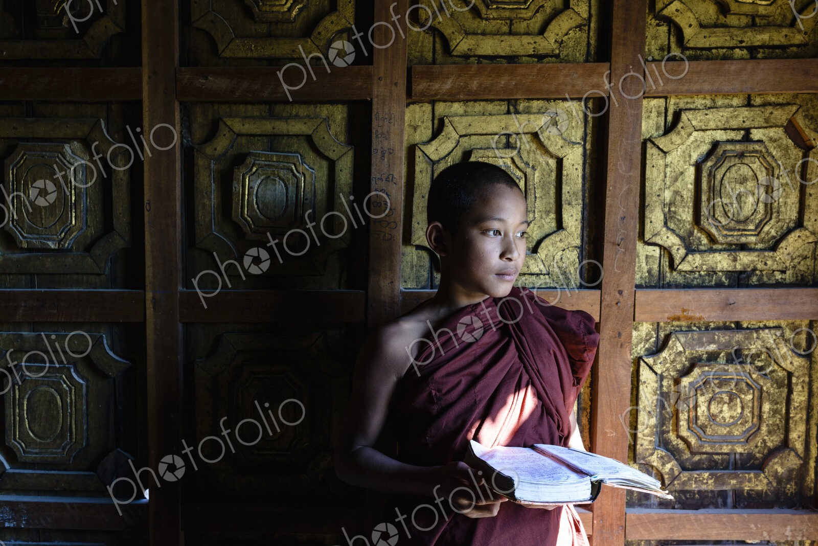 Asian monk-in-training holding book in temple