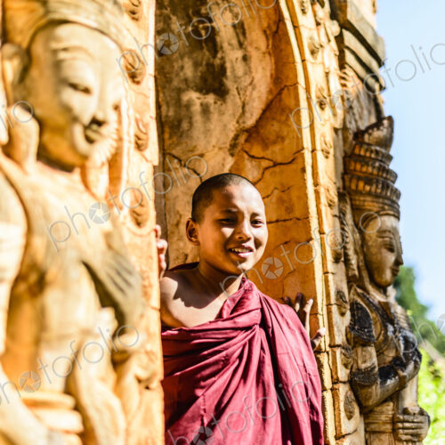 Asian monk-in-training peering around carved temple walls Asian monk-in-training peering around carved temple walls