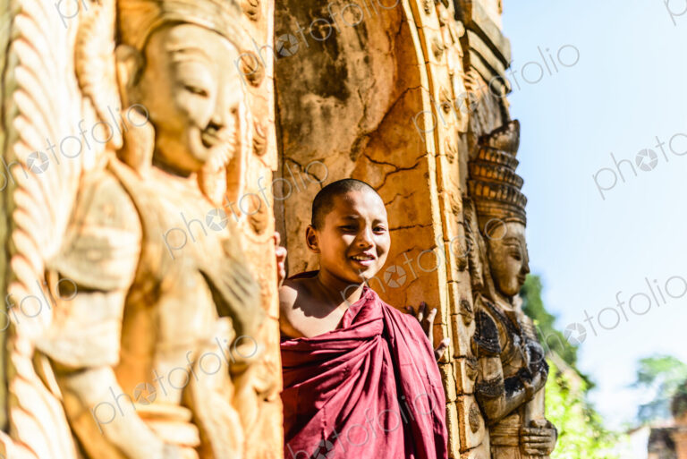 Asian monk-in-training peering around carved temple walls