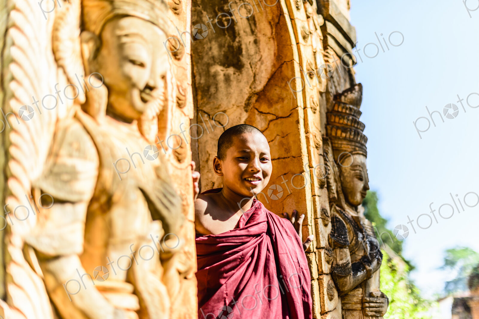 Asian monk-in-training peering around carved temple walls