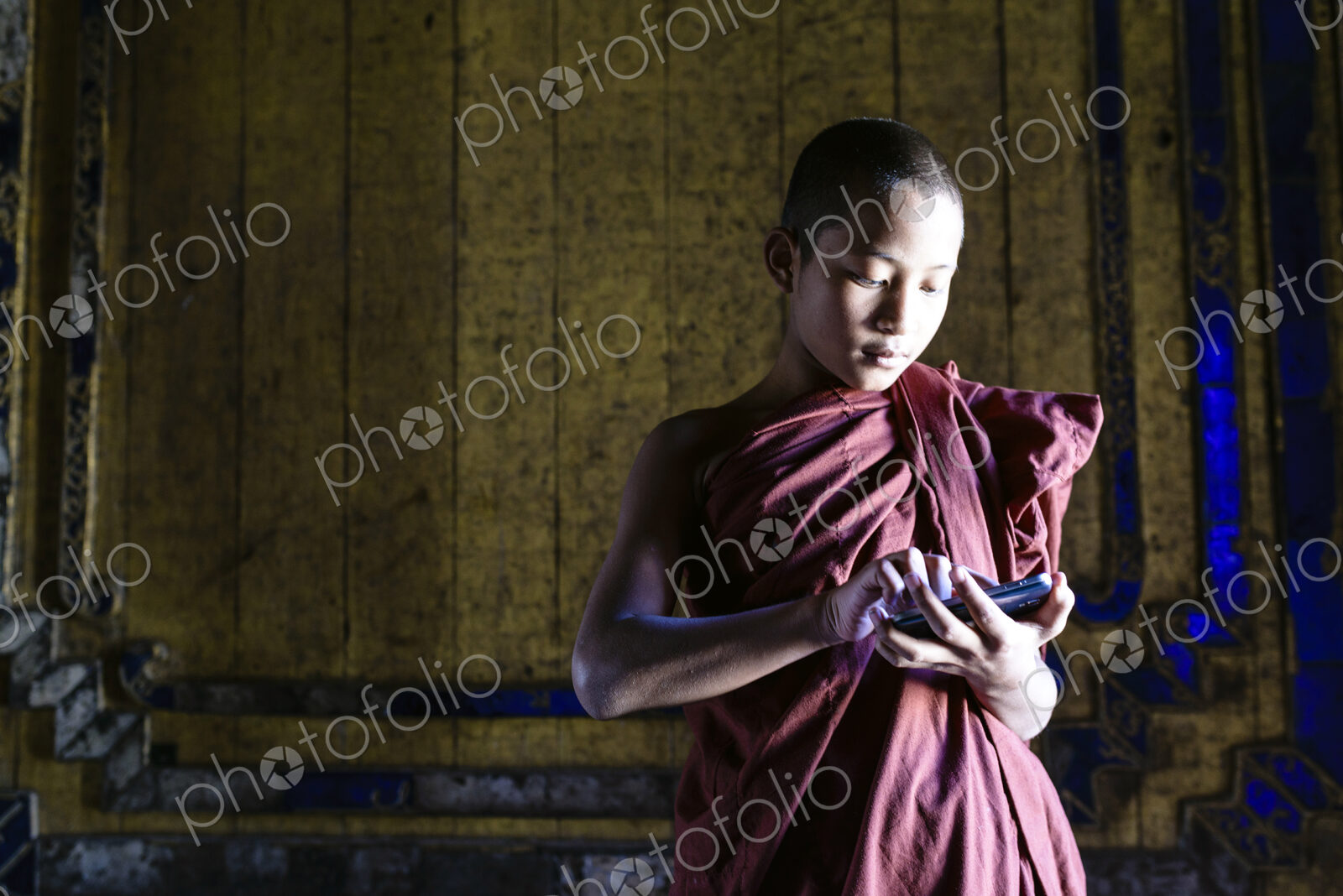Asian monk-in-training using cell phone in temple