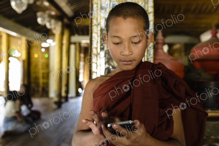 Asian monk-in-training using cell phone indoors