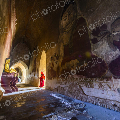 Asian monk-in-training walking in dilapidated stone temple Asian monk-in-training walking in dilapidated stone temple