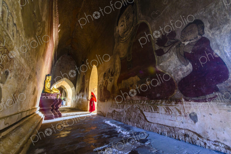 Asian monk-in-training walking in dilapidated stone temple