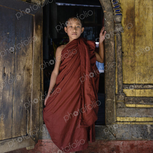 Asian monk-in-training walking out of temple archway Asian monk-in-training walking out of temple archway